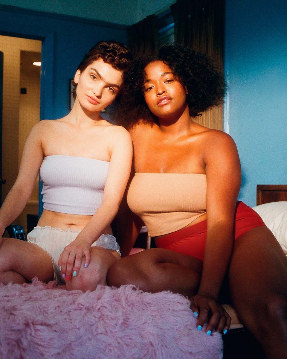 person two woman sitting on bed inside room human