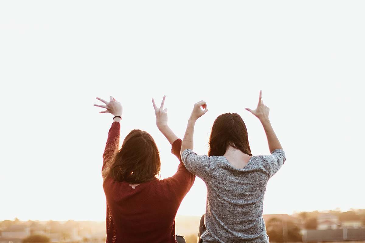 person two women sitting while making love hand sign at daytime human