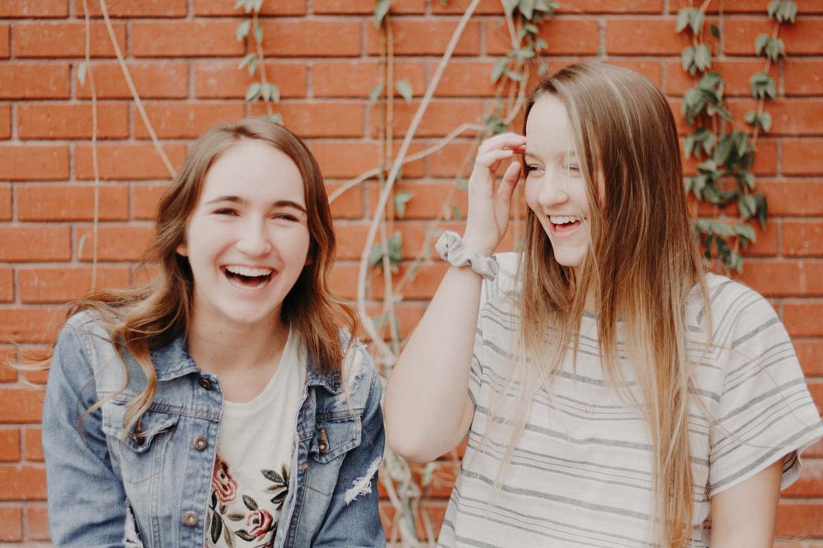 human two women smiling while standing near wall person