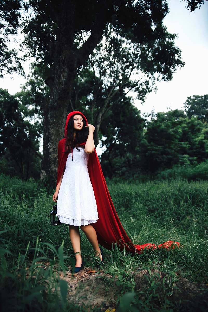 human woman cosplaying little riding hood near tree person