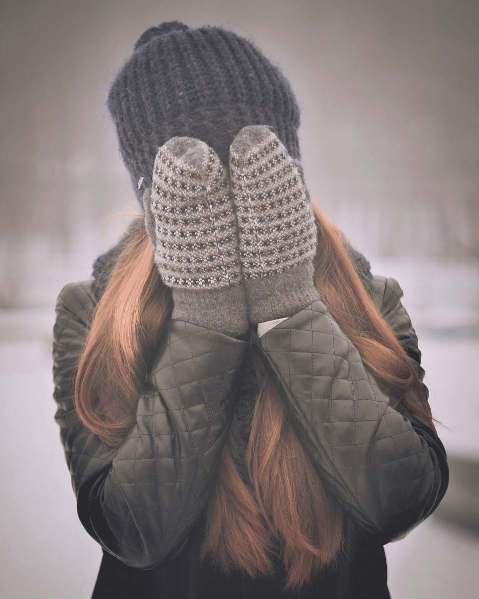 person woman covering her face mittens
