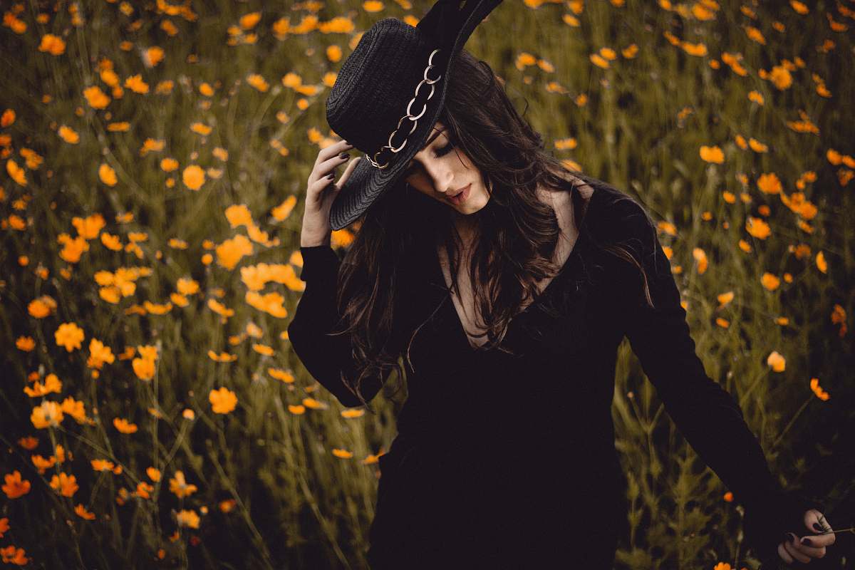human woman holding hat surrounding yellow petaled flowers person