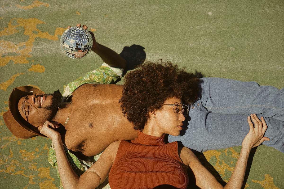 person woman in brown turtleneck sleeveless top lying on man's stomach wearing green button-up collared shirt holding disco ball human