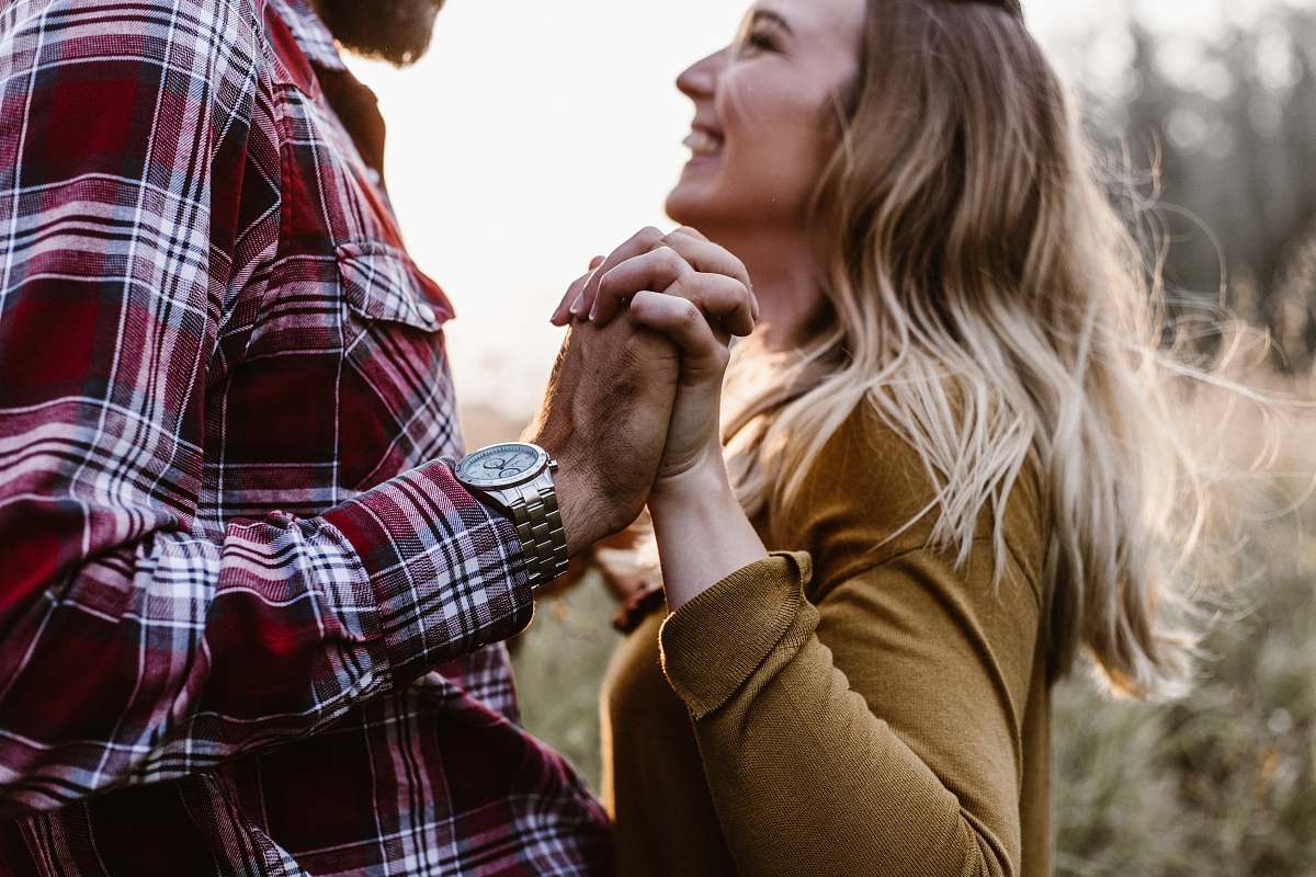person woman in front of man holding each hands each other near green trees human