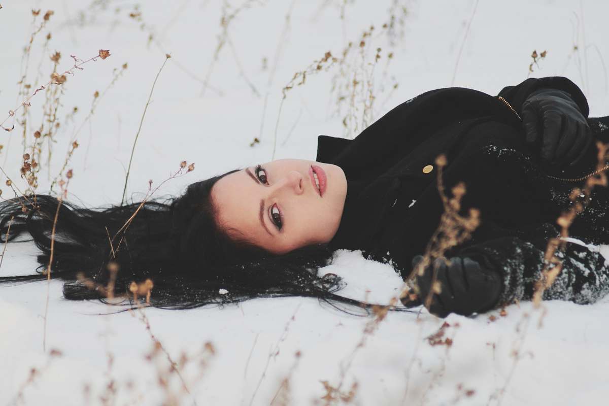 person woman laying on snowy ground woman