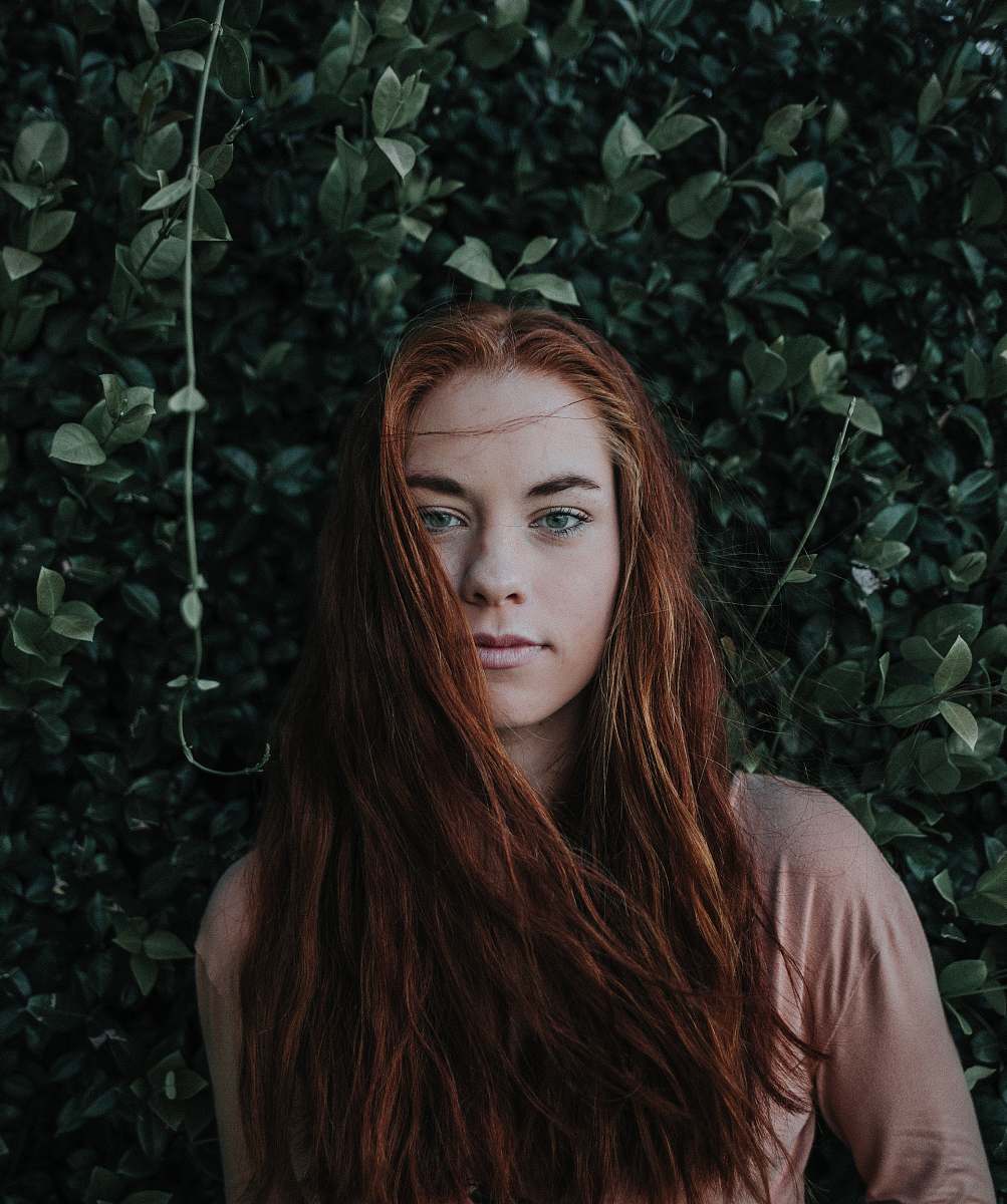 human woman leaning on green leaf plant during daytime woman