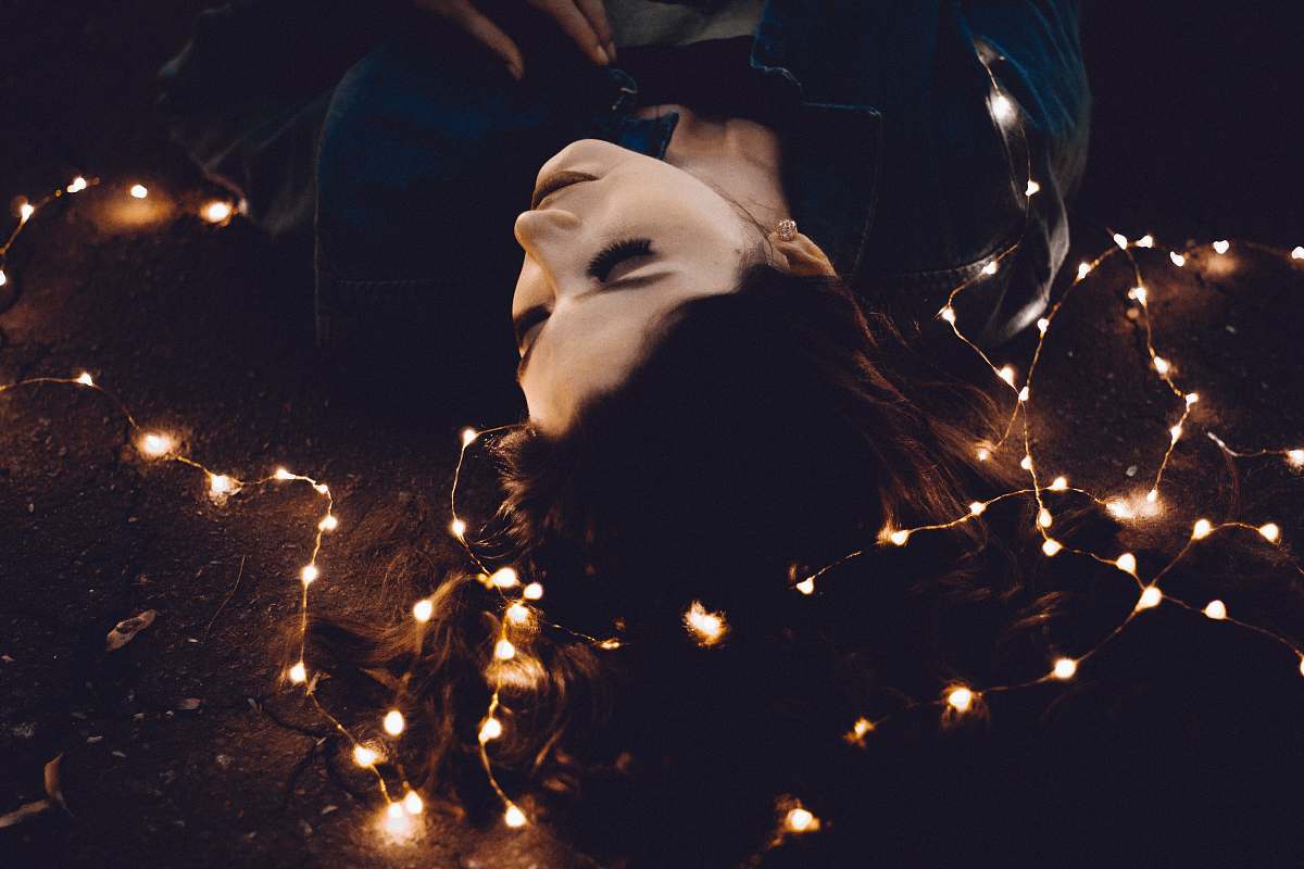 woman woman lying on yellow string lights human