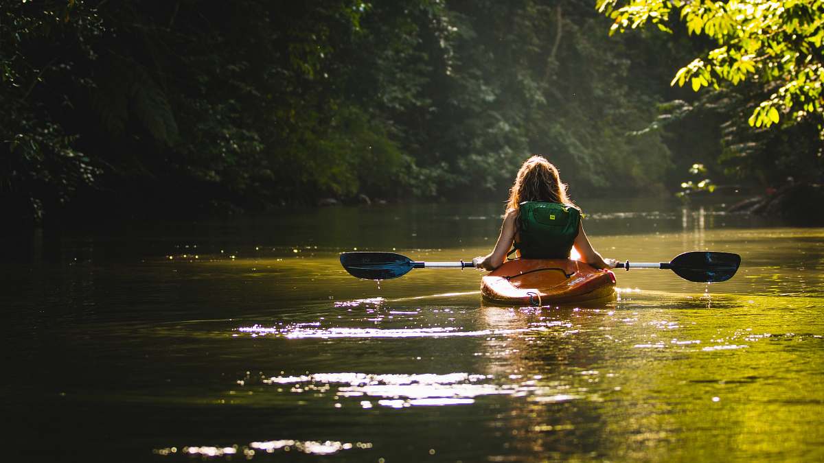 canoe woman on kayak on body of water holding paddle kayak