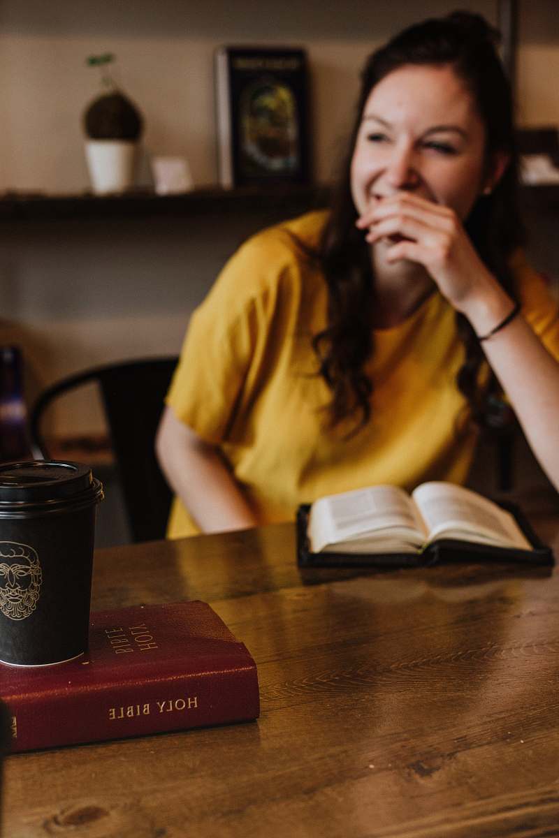 person woman siting on chair near on holy bible human