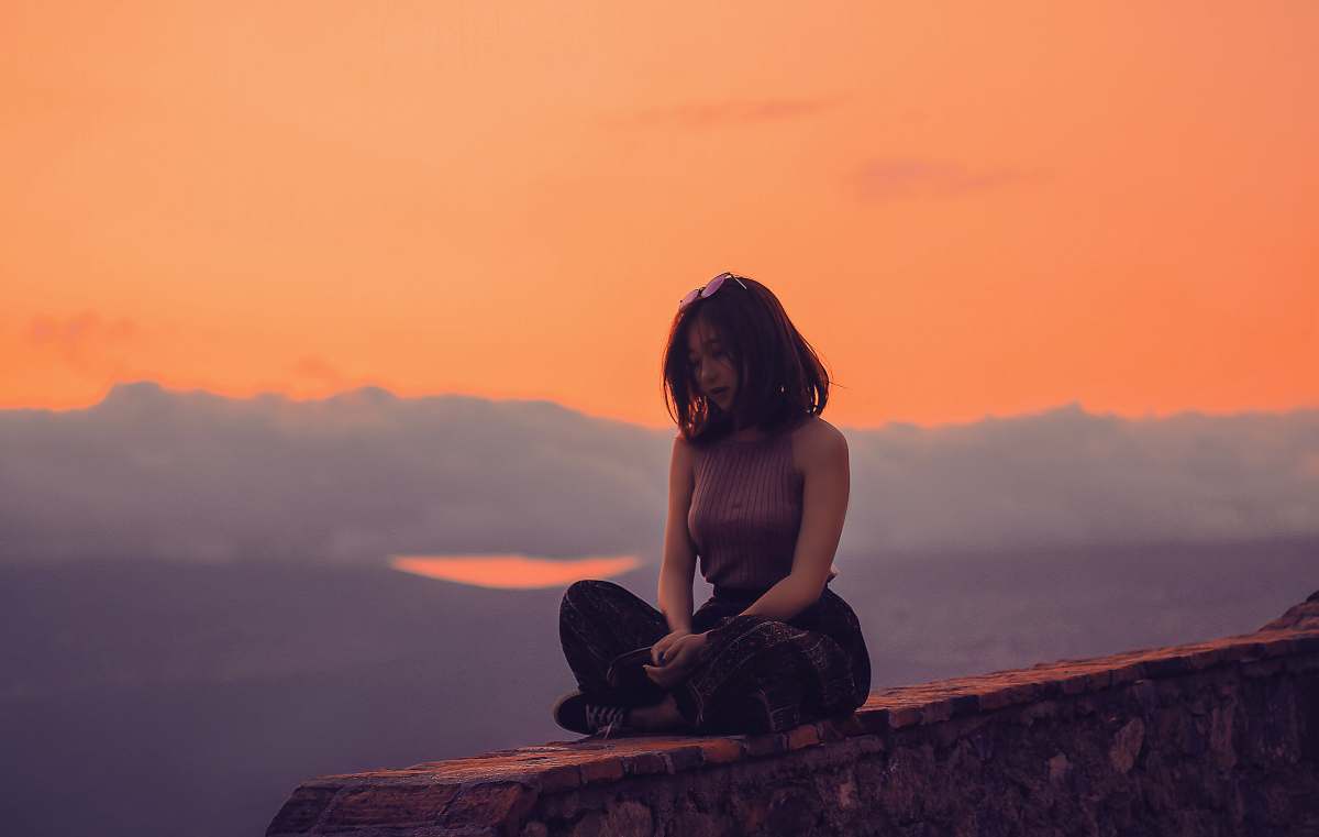 person woman sitting on a cliff yoga