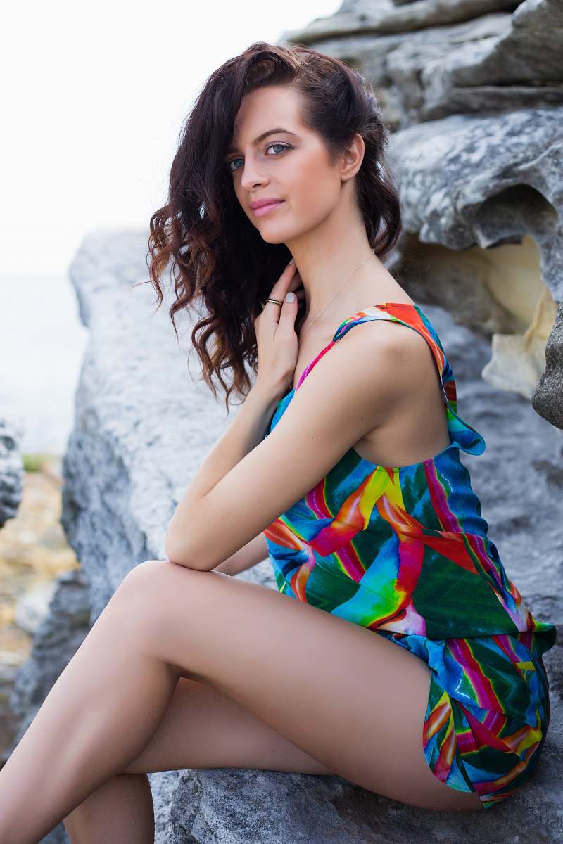 female woman sitting on gray boulder during daytime bikini