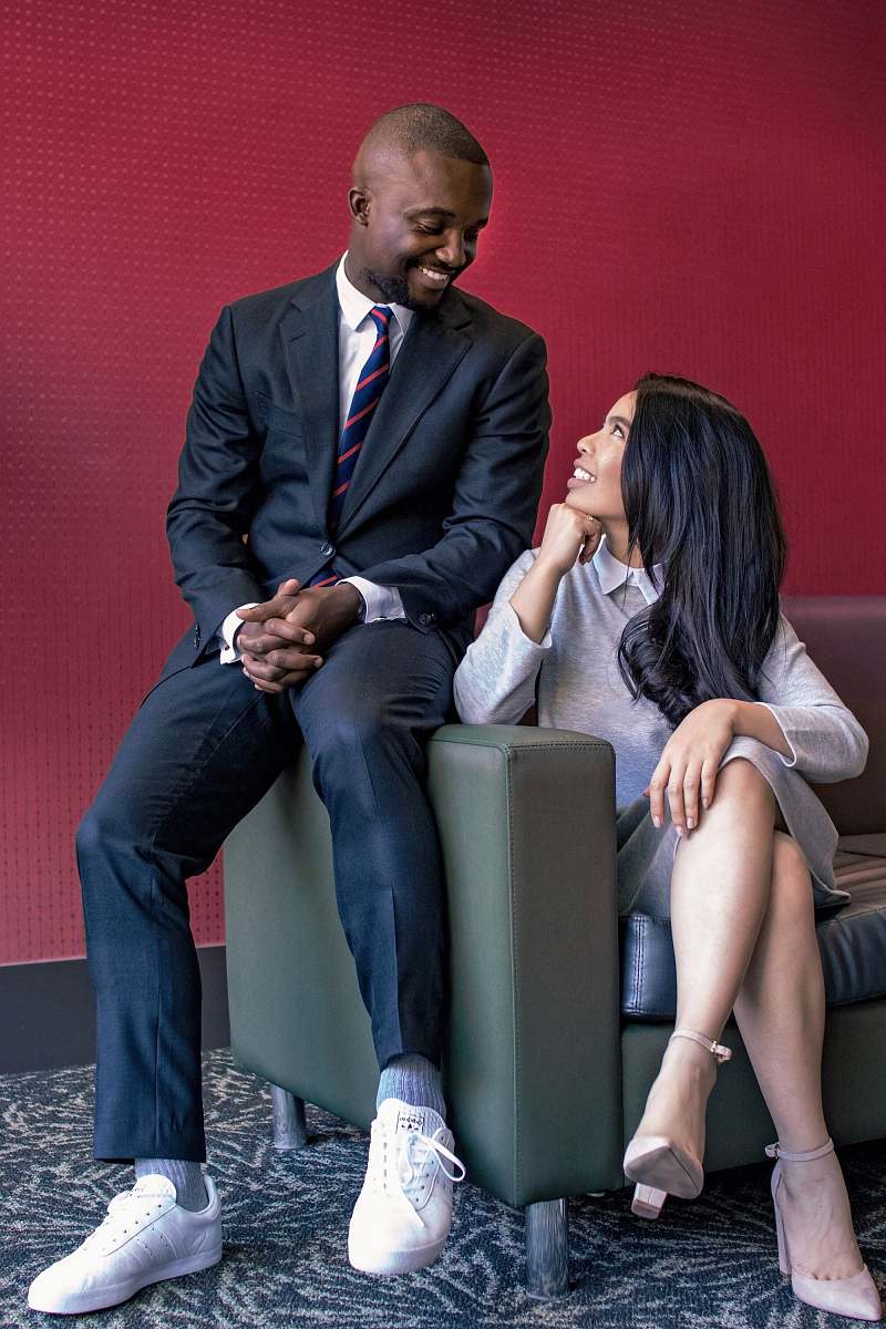 human woman sitting on gray leather sofa beside a man while looking each other person