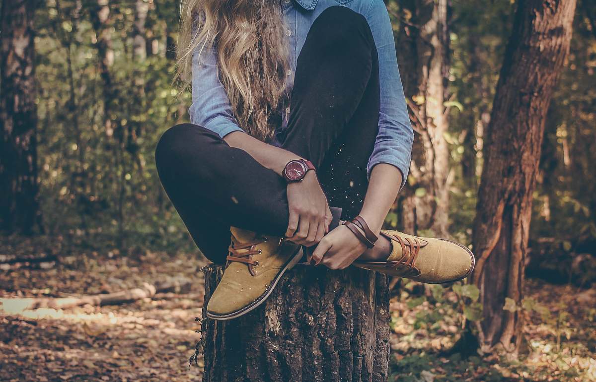 person woman sitting on tree stump watch