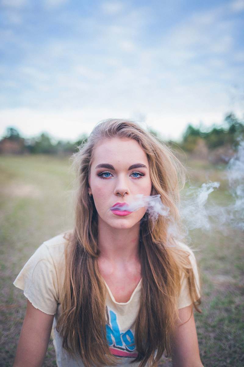 person woman smoking while sitting on green grass human