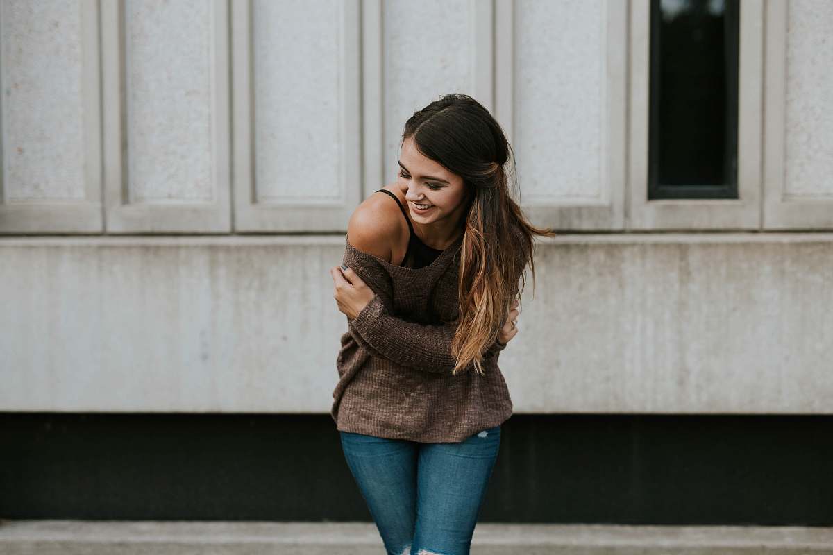 person woman standing behind white wall woman