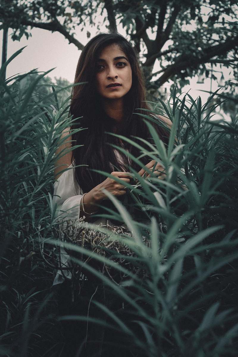human woman standing between green plants person