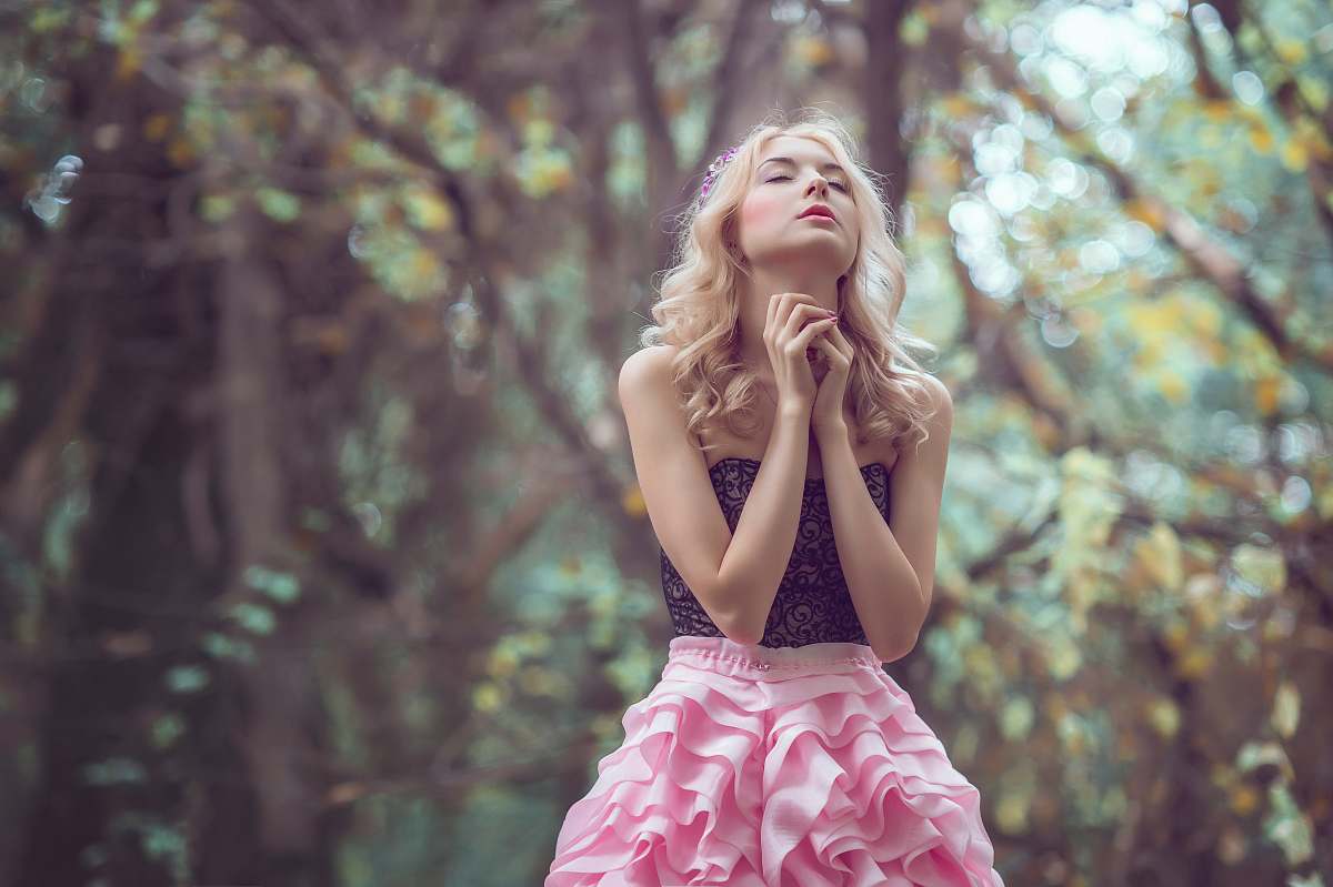 person woman standing in the middle of the forest holding hands together during daytime girl