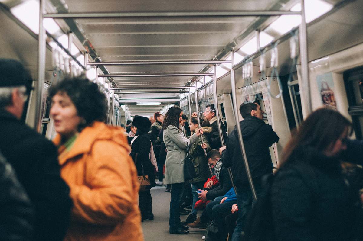 person woman standing inside train surrounded by people subway