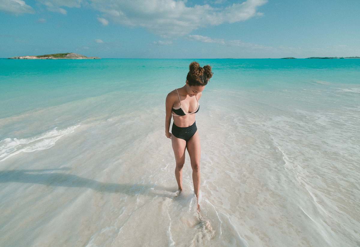 beach woman wearing bikini swimsuit while standing on beach seashore at daytime water