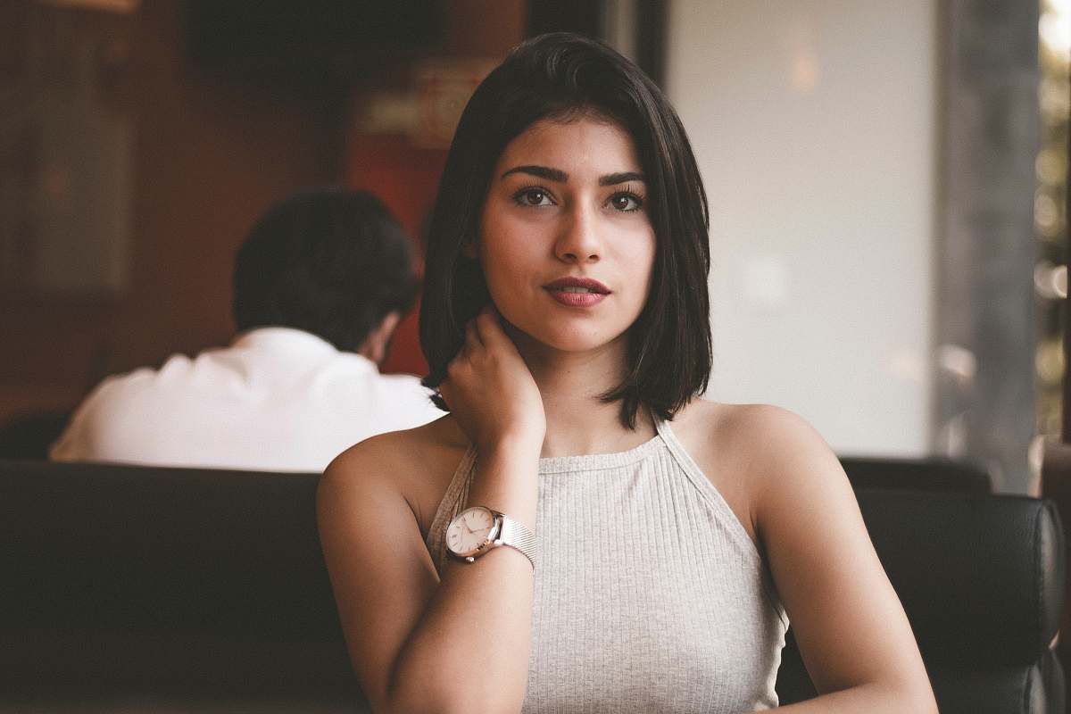 person woman wearing gray spaghetti strap shirt sitting on black leather sofa close-up photo human