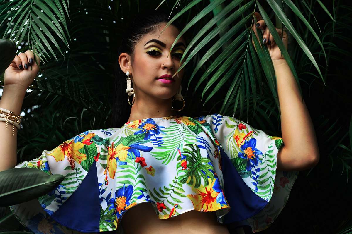 woman woman wearing multicolored floral crop-top holding green palm leaves fashion