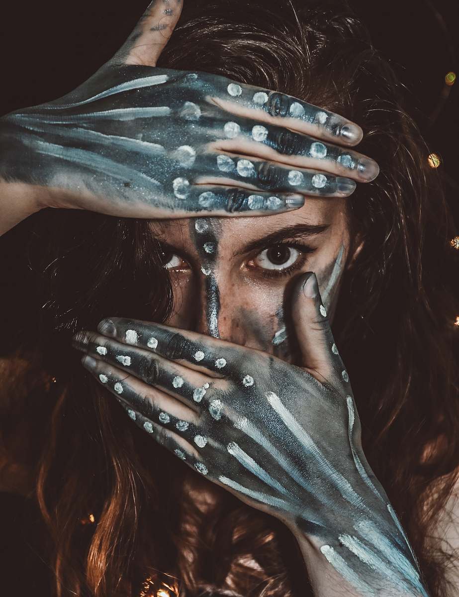person woman with black and white body paint covering half of her face with her hands human