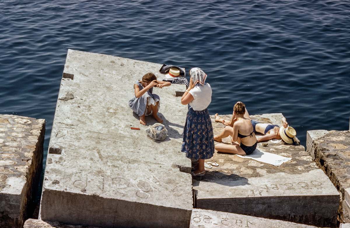 person Women in swimsuits and vintage clothing sunbathing on cement cubes by the sea human