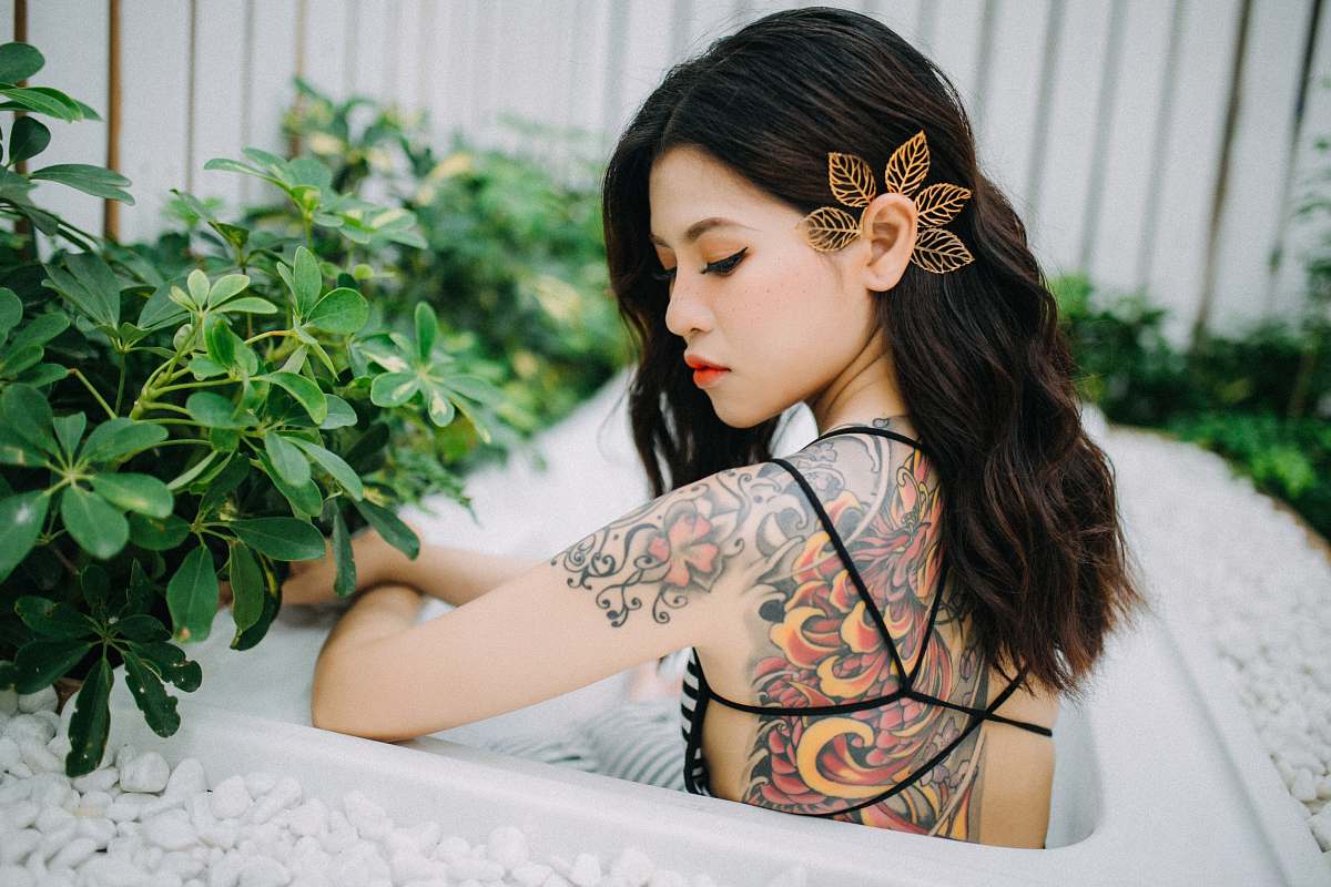 human women's orange and black floral back tattoo person