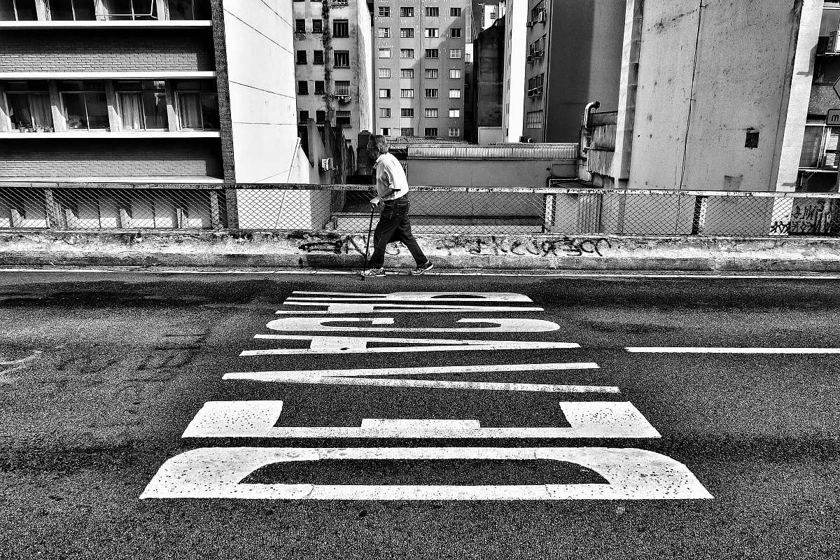 people gray scale photography of person walking beside pave road black-and-white