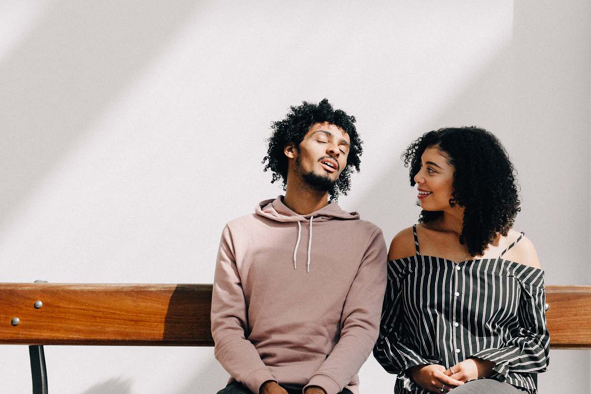 people man in brown drawstring pullover hoodie sitting on brown bench beside woman hair