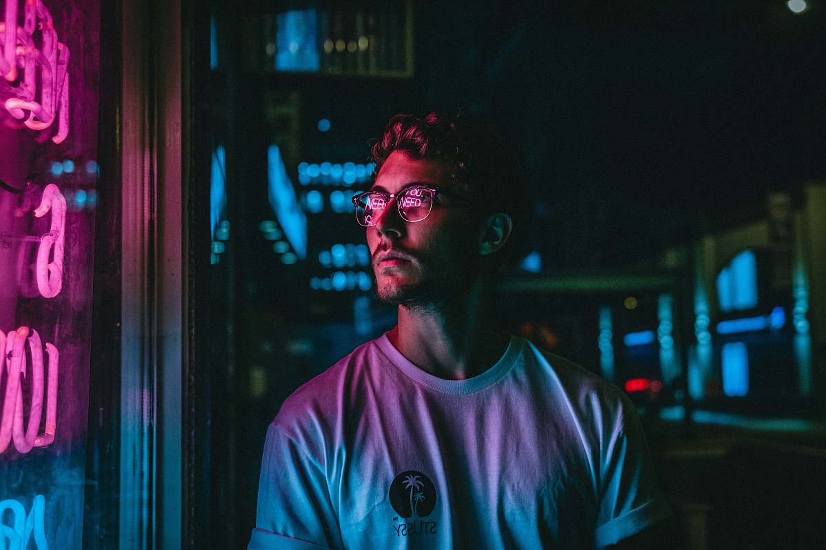 people man looking at glass storefront windowpane during night neon