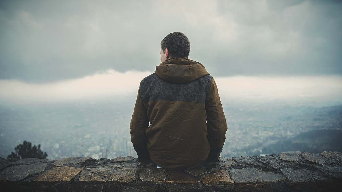 people man sitting on brown concrete surface while staring sideway human