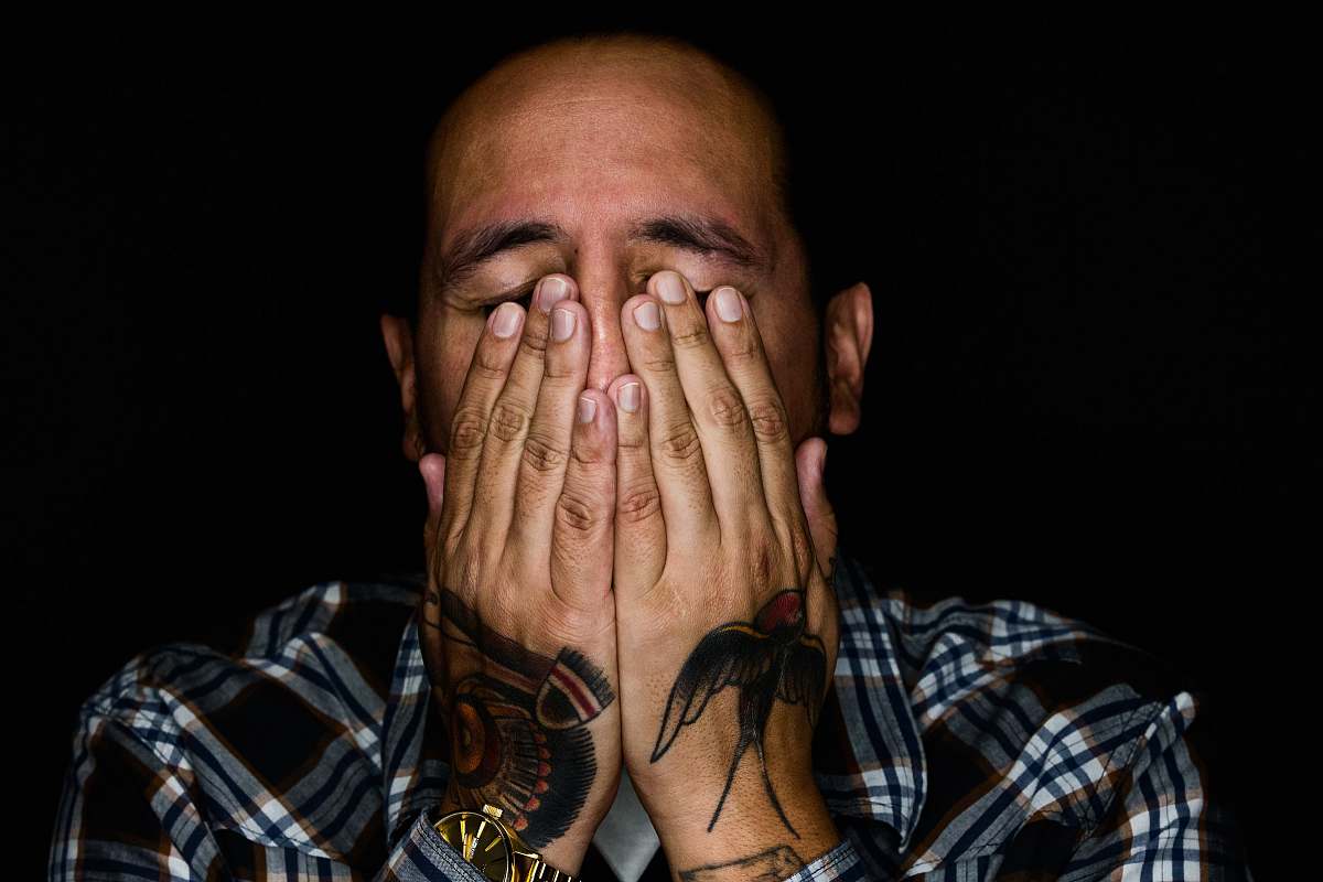 people man wearing black, white, and gray plaid sport shirt covering his face tattoo