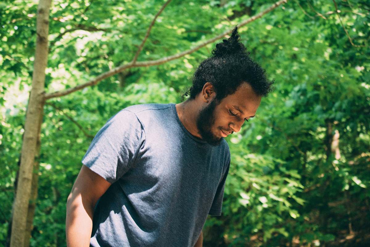 people man wearing grey crew-neck t-shirt standing under tree during daytime forest