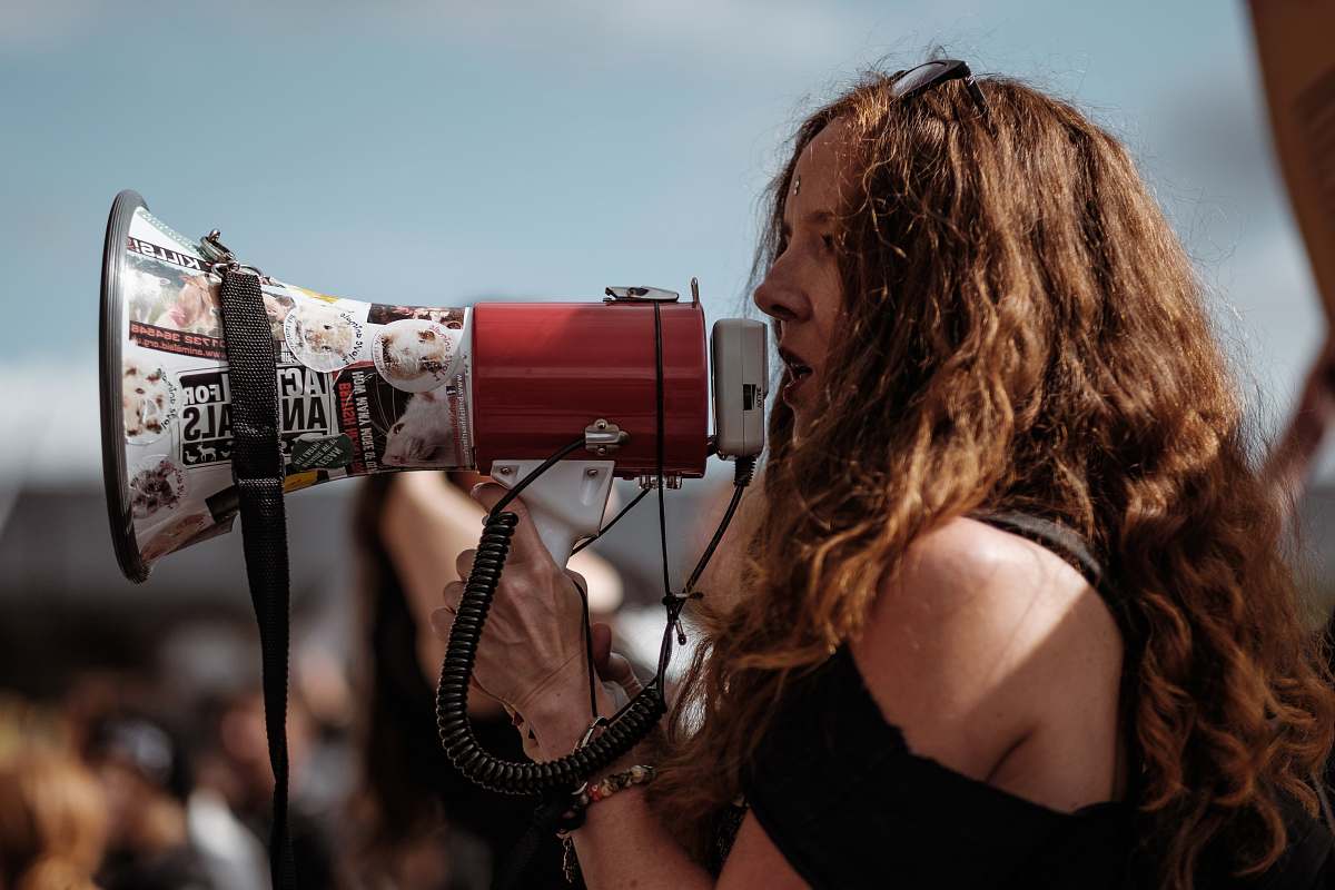 people selective focus photography of woman wearing black cold-shoulder shirt using megaphone during daytime human