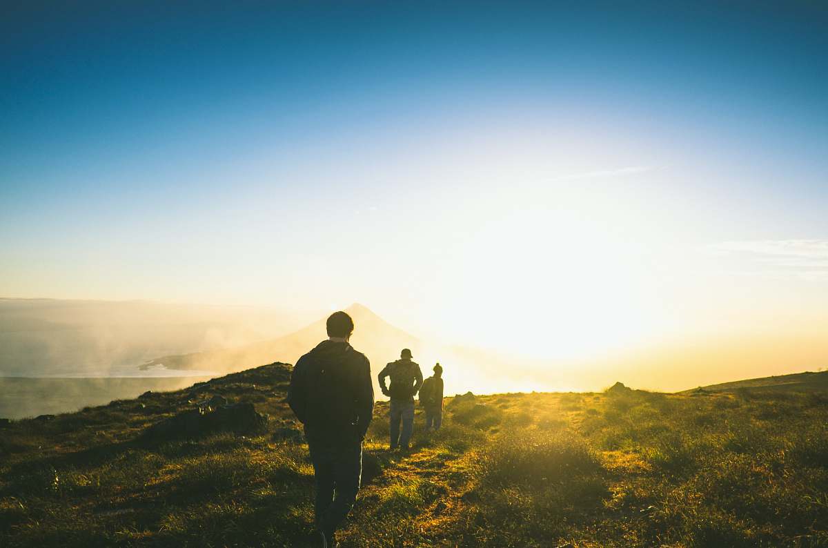 people silhouette of three men falling in line while walking during golden hour hiking