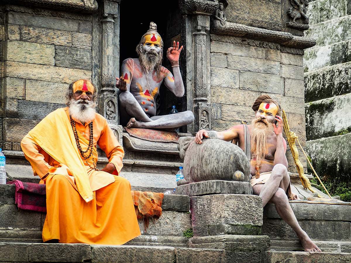 people three monks sitting on concrete temple during daytime human