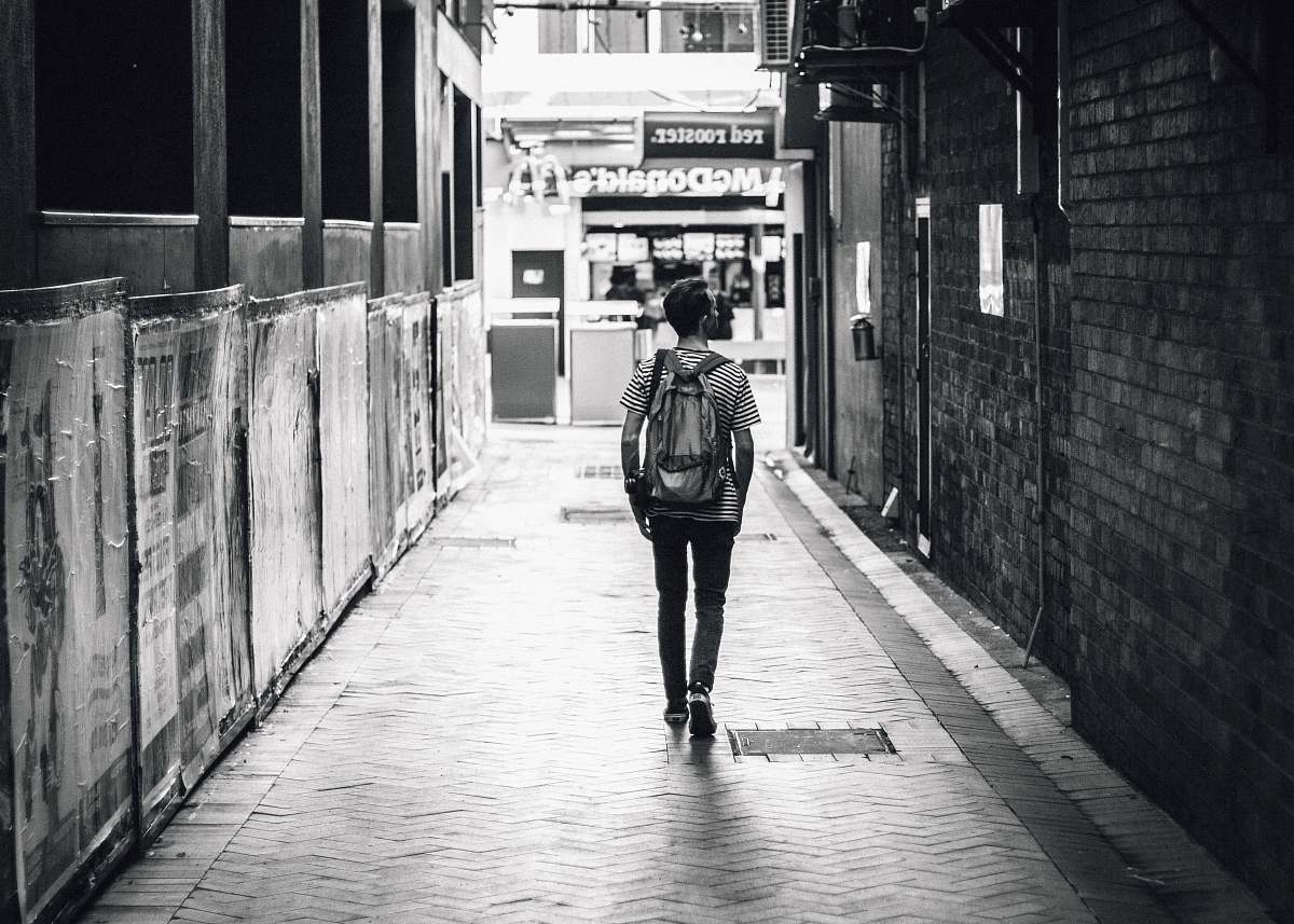  man walking between concrete buildings 