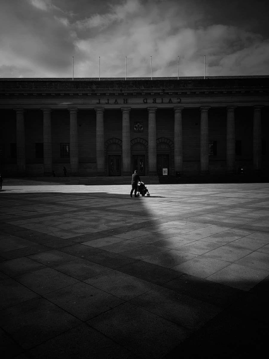 city grayscale photography of person pushing stroller building