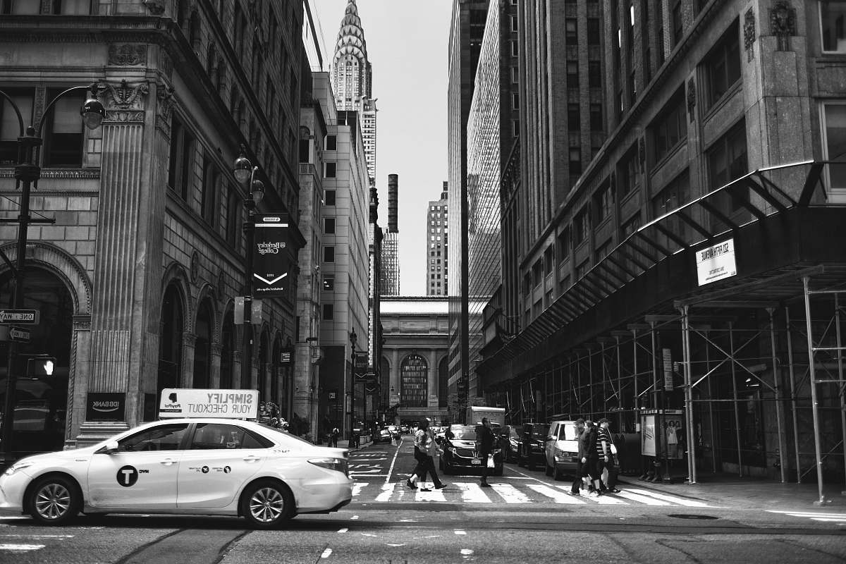 road grayscale photography of sedan beside pedestrian urban