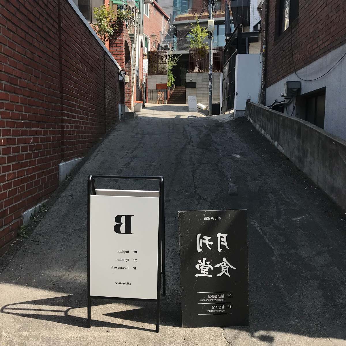 city black and white road signs between buildings road