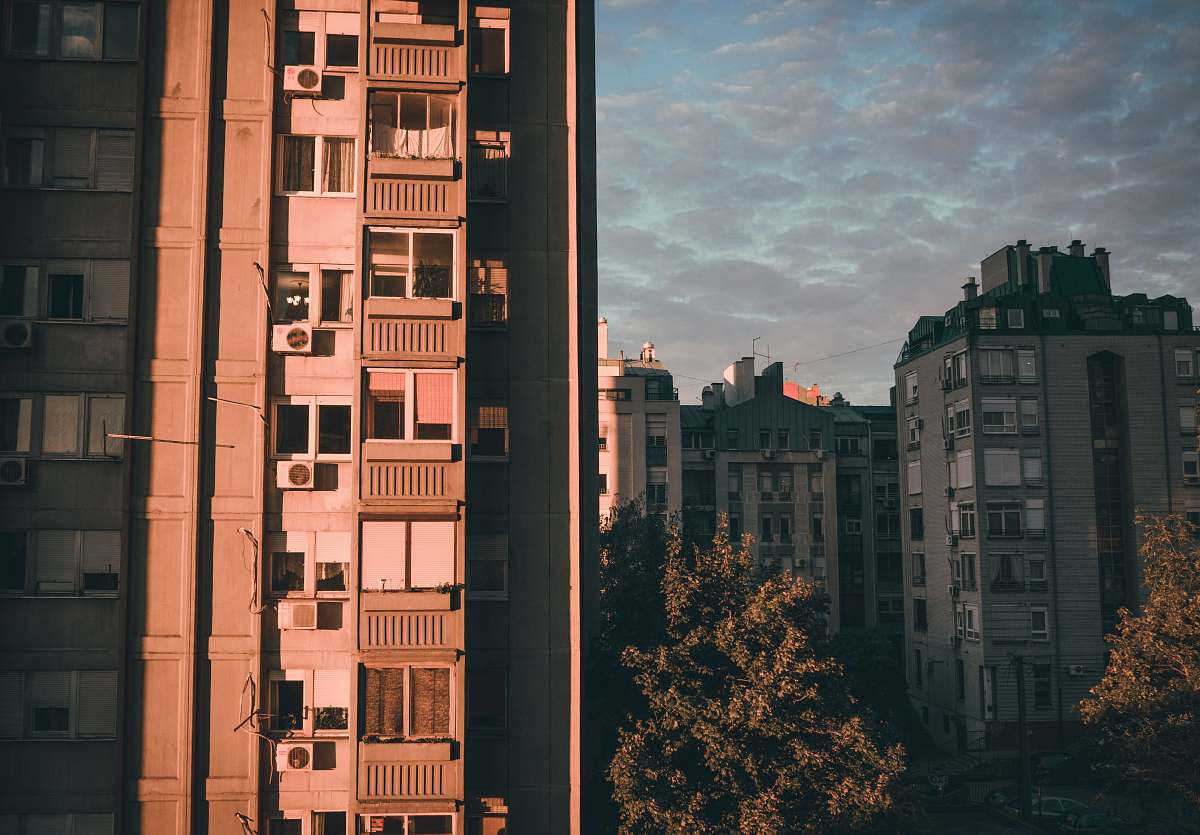 city brown concrete building beside green tree high rise