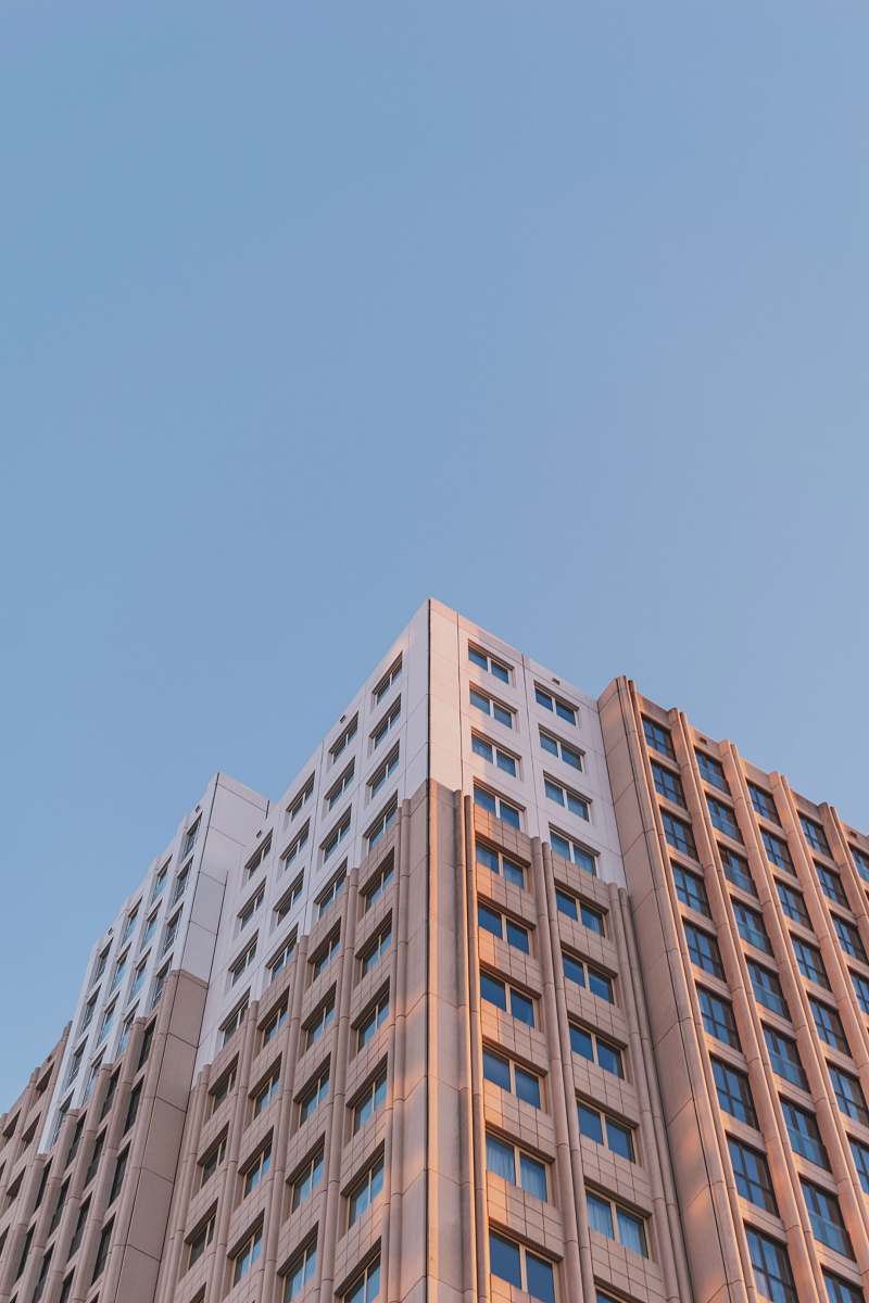 city brown concrete building under blue sky high rise