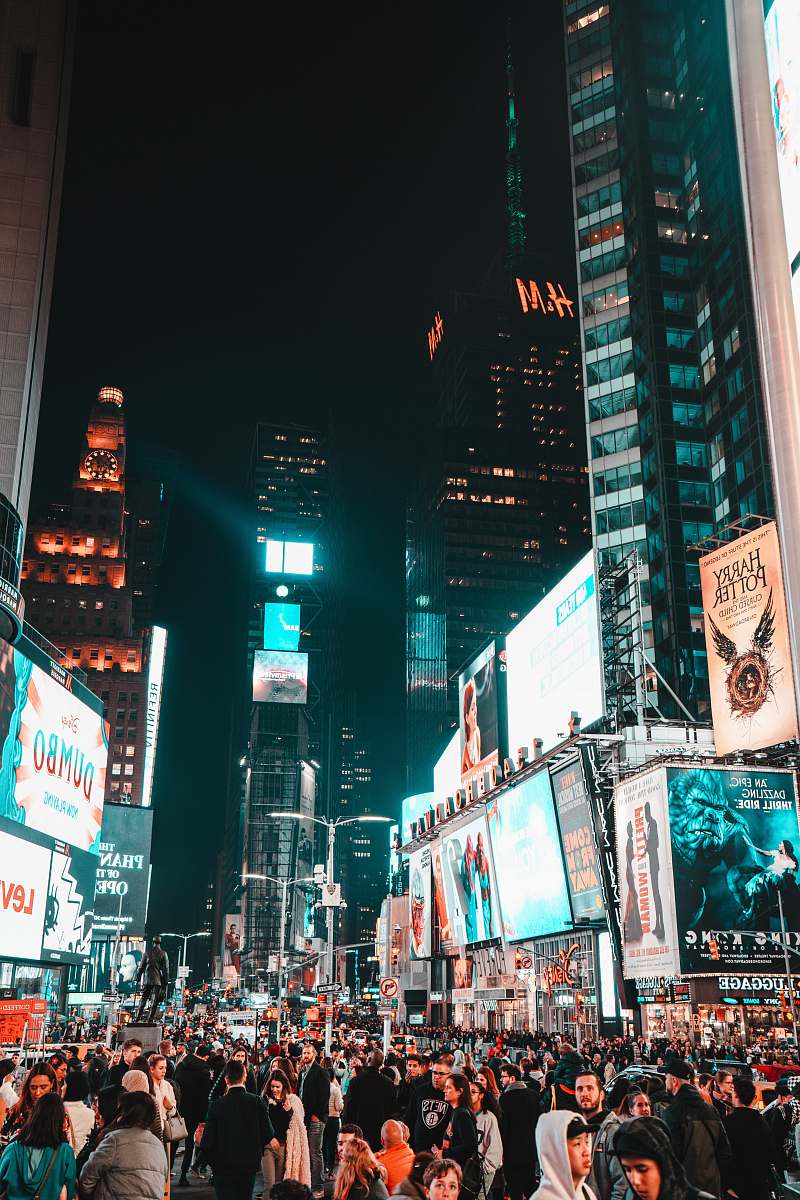 city crowd walking between buildings with e-billboard during night metropolis