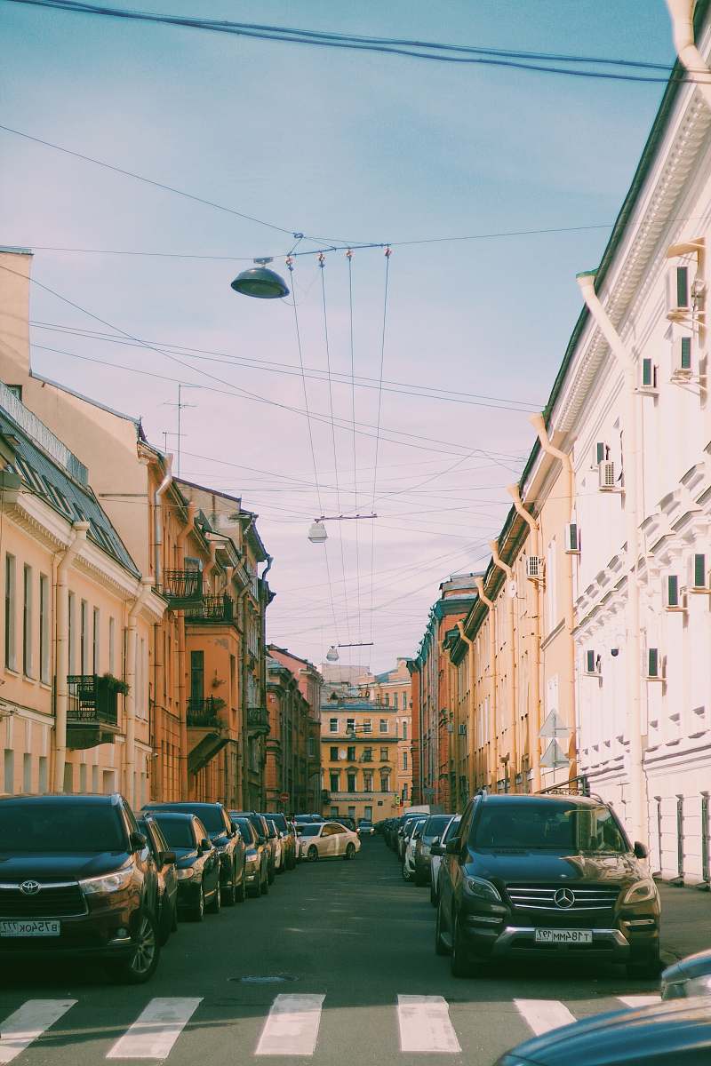 city different vehicles on road near building under blue and white skies during daytime road