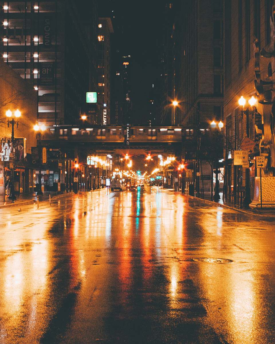 city gray concrete road between buildings at night metropolis