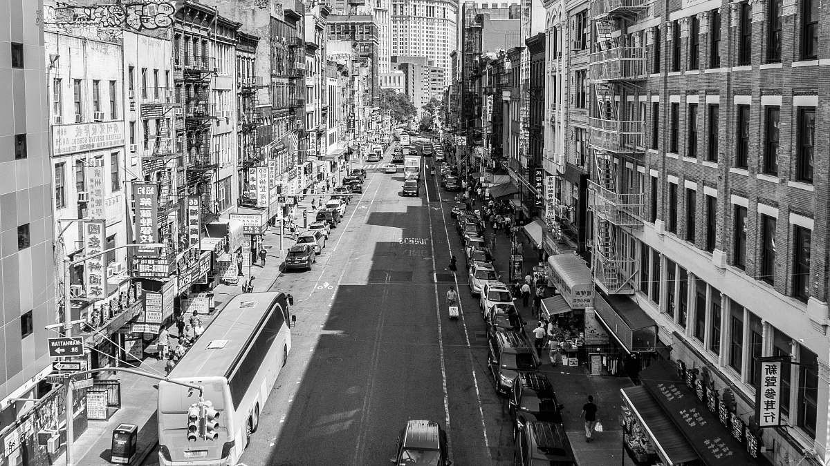 city grayscale photo of vehicles on roadway between buildings black-and-white