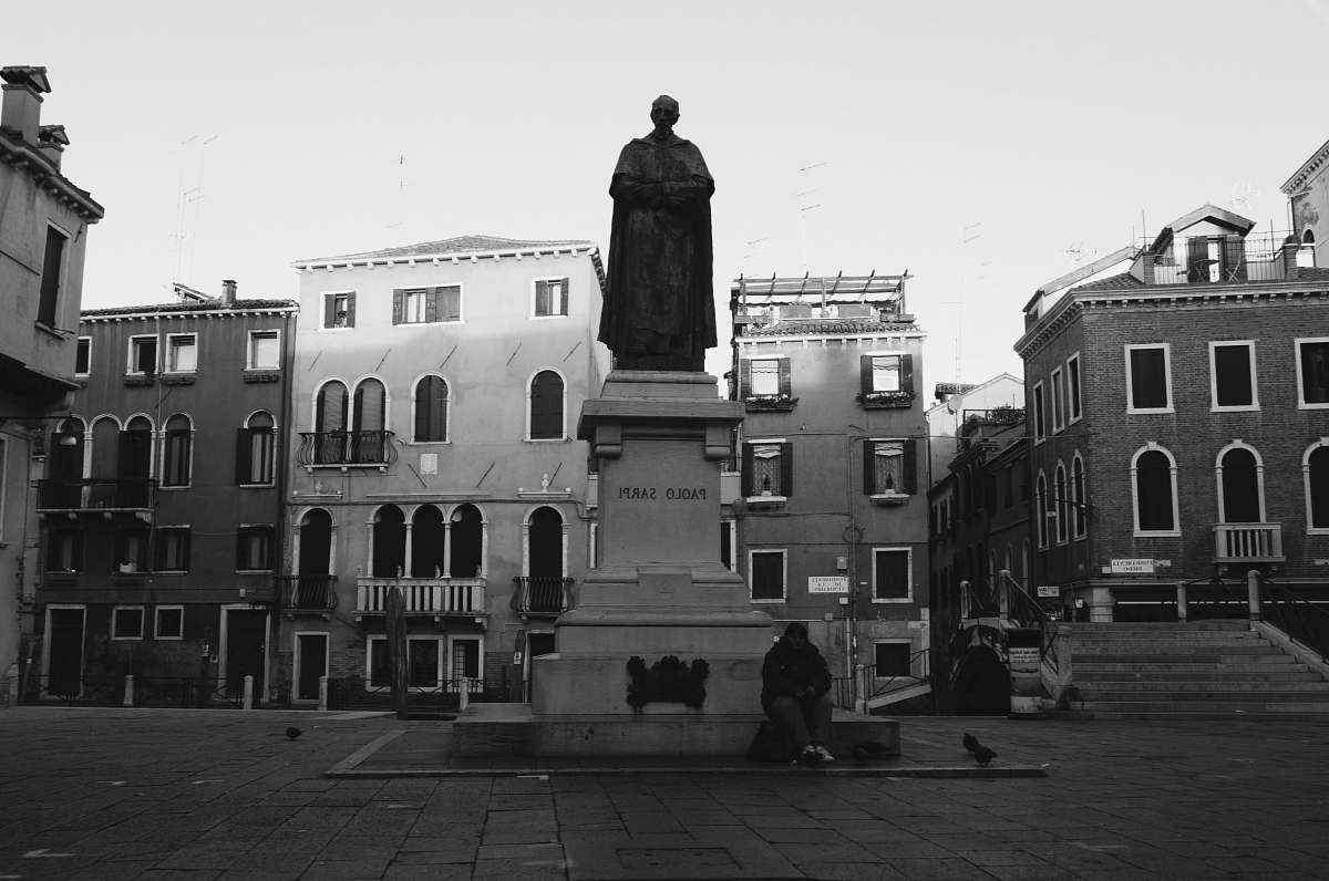 city grayscale photography of man statue with buildings background black-and-white
