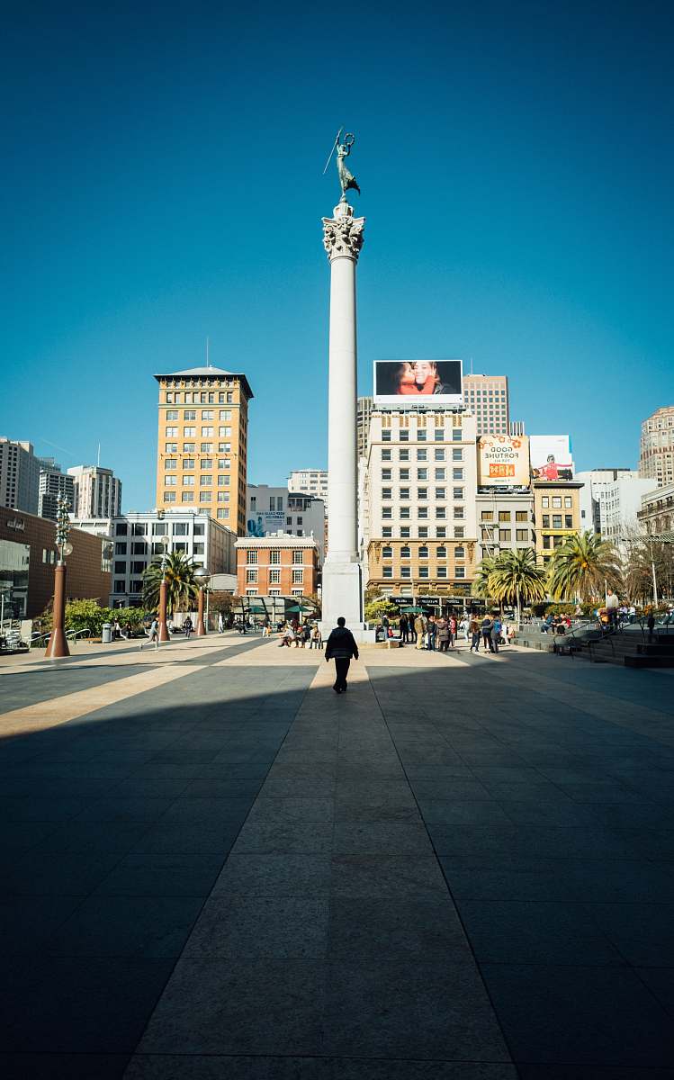 city man walking infront of white tower downtown