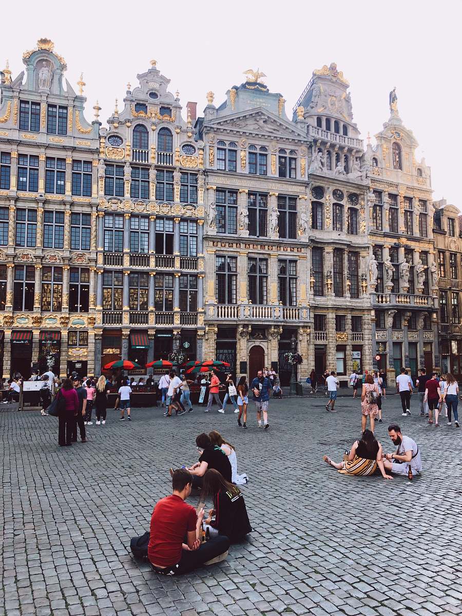 downtown people sitting and standing beside high buildings during daytime town